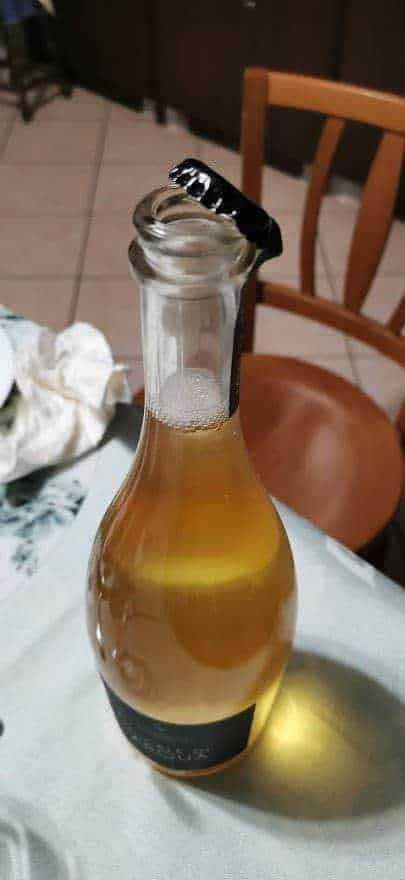 Bibita gassata in bottiglia di vetro su tavolo, ambiente casalingo, dettaglio di bevanda fresca, consumo di bevande analcoliche, atmosfera rilassante, Ottimale per contenuti su appunti e blog di lifestyle e beverage.