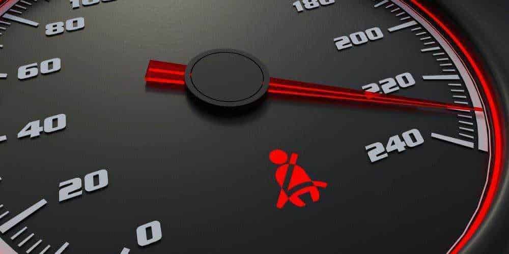 Tachimetro auto con indicatore di velocità, simbolo di cintura di sicurezza accanto, dettaglio di sicurezza e velocità del veicolo.