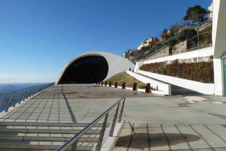 Moderno edificio architettonico vicino al mare con design innovativo e pareti bianche, situato su una scogliera con viste panoramiche sulla costa.