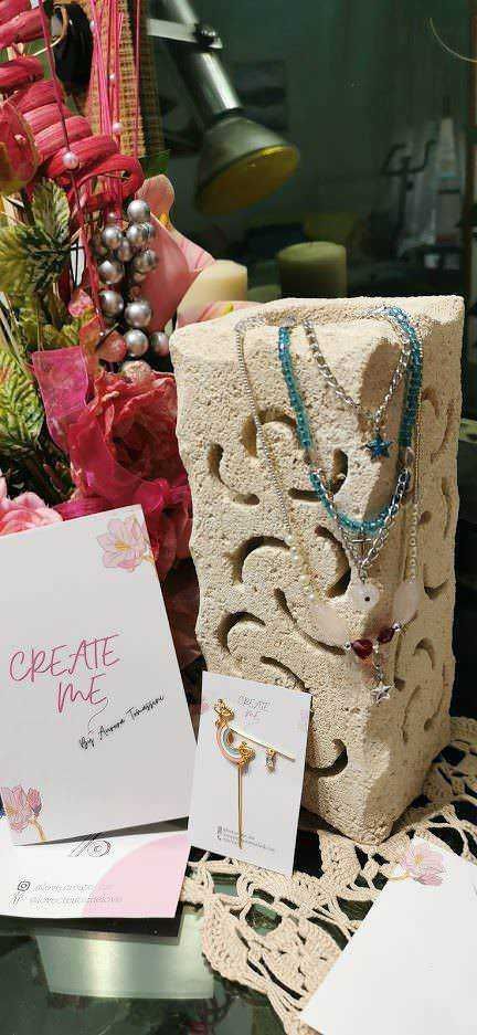 Bracciali e collane colorate esposte con pietre e charms, decorazioni natalizie e biglietti di auguri, setup di gioielli artigianali su uno sfondo di decorazioni festive, ideale per negozi di bijoux fatti a mano.