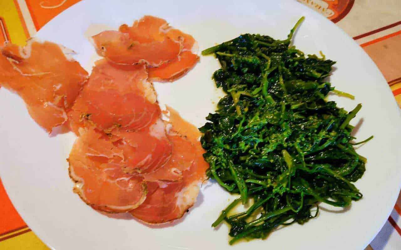 Prosciutto crudo e verdure saltate in padella, piatto tradizionale italiano, ideale per antipasto o secondo, ricco di sapore e qualità gastronomiche autentiche.