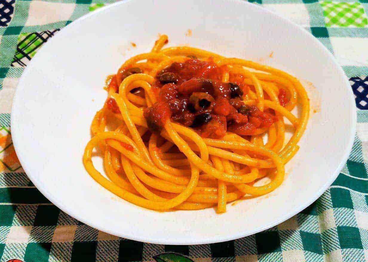 Spaghetti alla bolognese con sugo di pomodoro e carne, piatto italiano tradizionale, pasta lunga e ricca di gusto, su tavolo con tovaglia a quadretti colorata.