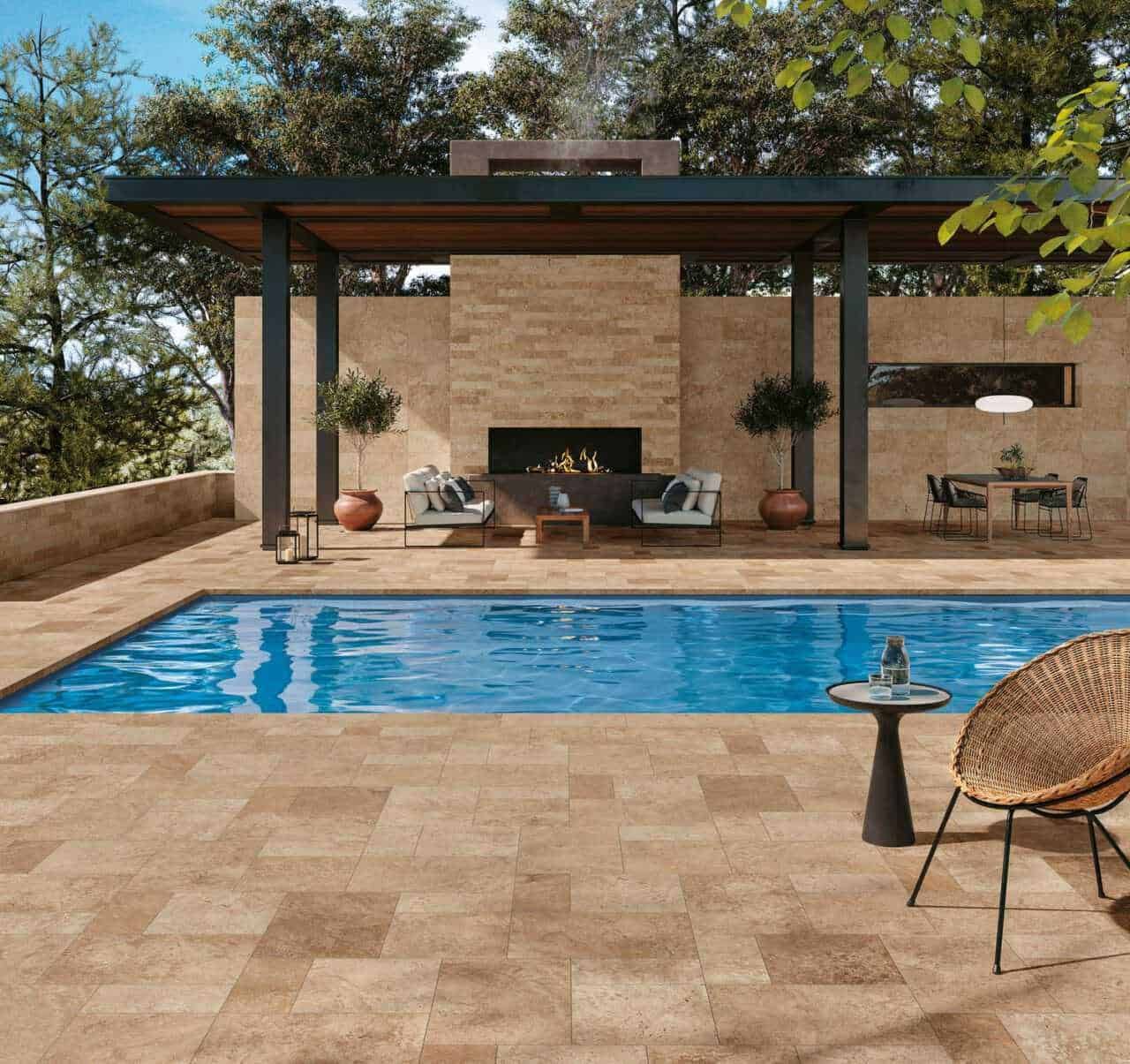 Relaxing outdoor pool area with modern lounge furniture, fireplace, and lush greenery in a stylish home setting. Perfect for leisure and outdoor entertainment.