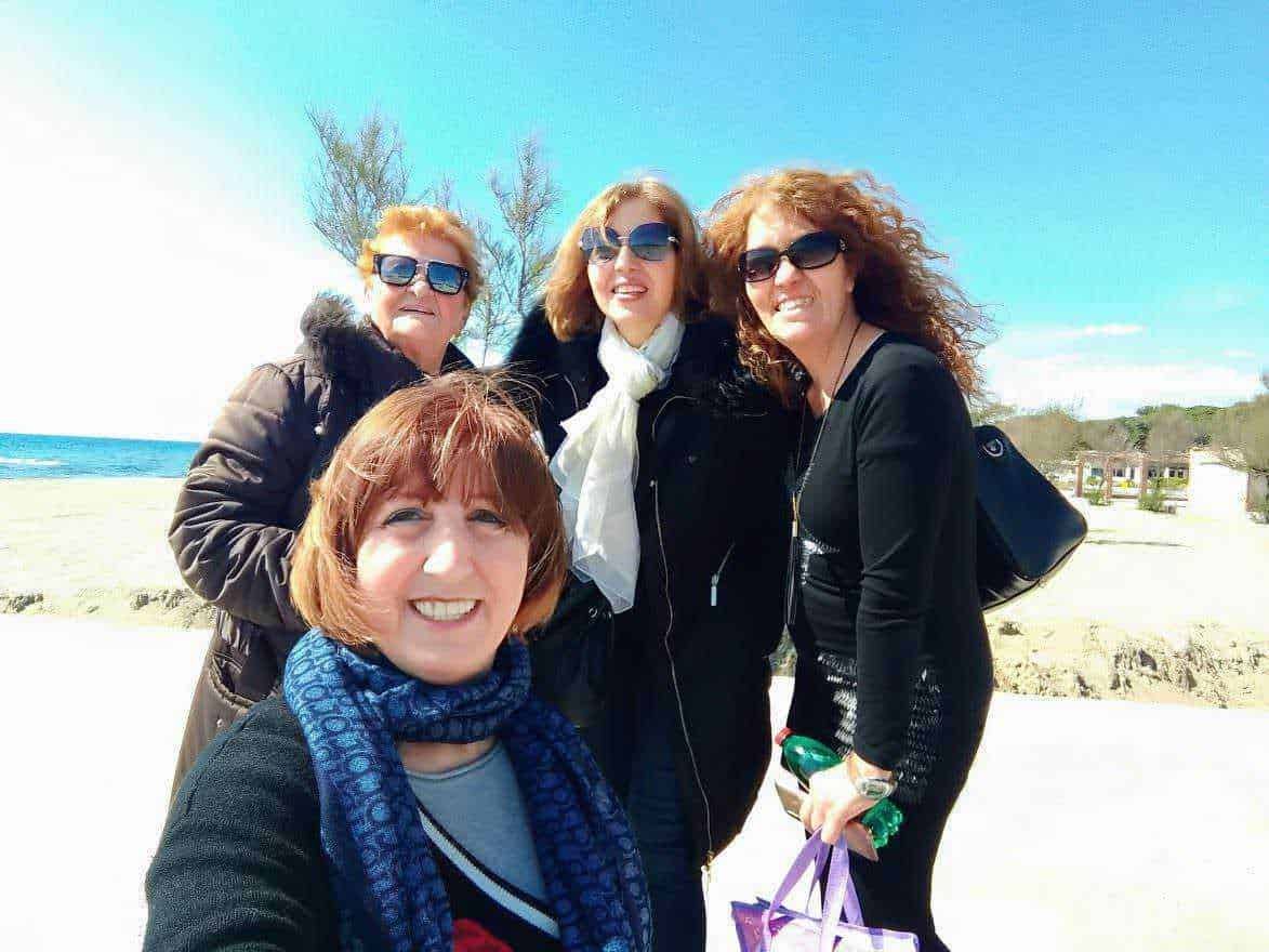Persone sorridenti che si godono una giornata sulla spiaggia con il mare e il cielo azzurro, perfette per immagini di viaggi, vacanze e amicizia, ideali per blog sul turismo e lifestyle.