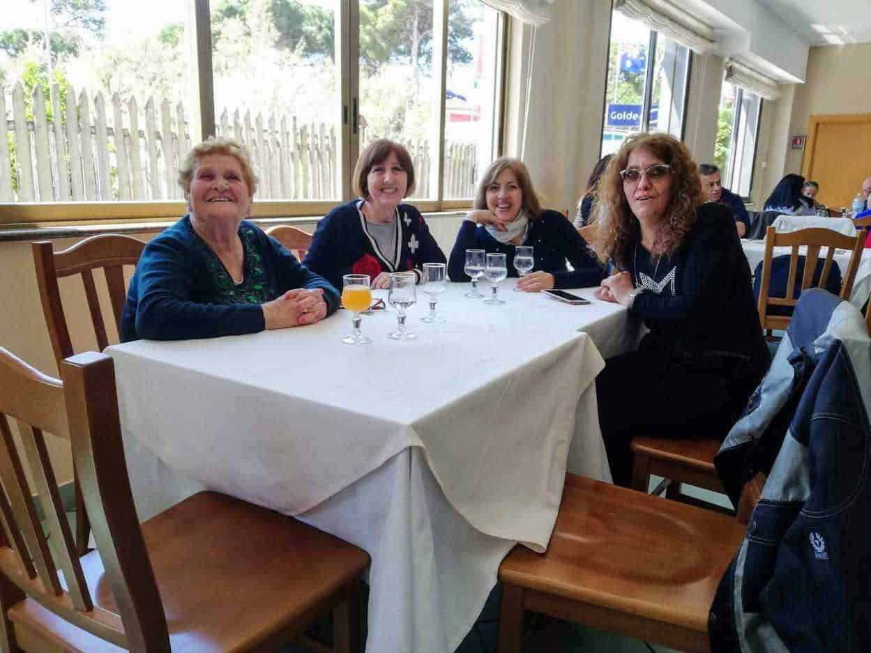 Ragazze sorridenti sedute a tavola in un ristorante durante un evento sociale, con bicchieri di bevande e atmosfera conviviale, perfetto per articoli su incontri e momenti speciali.