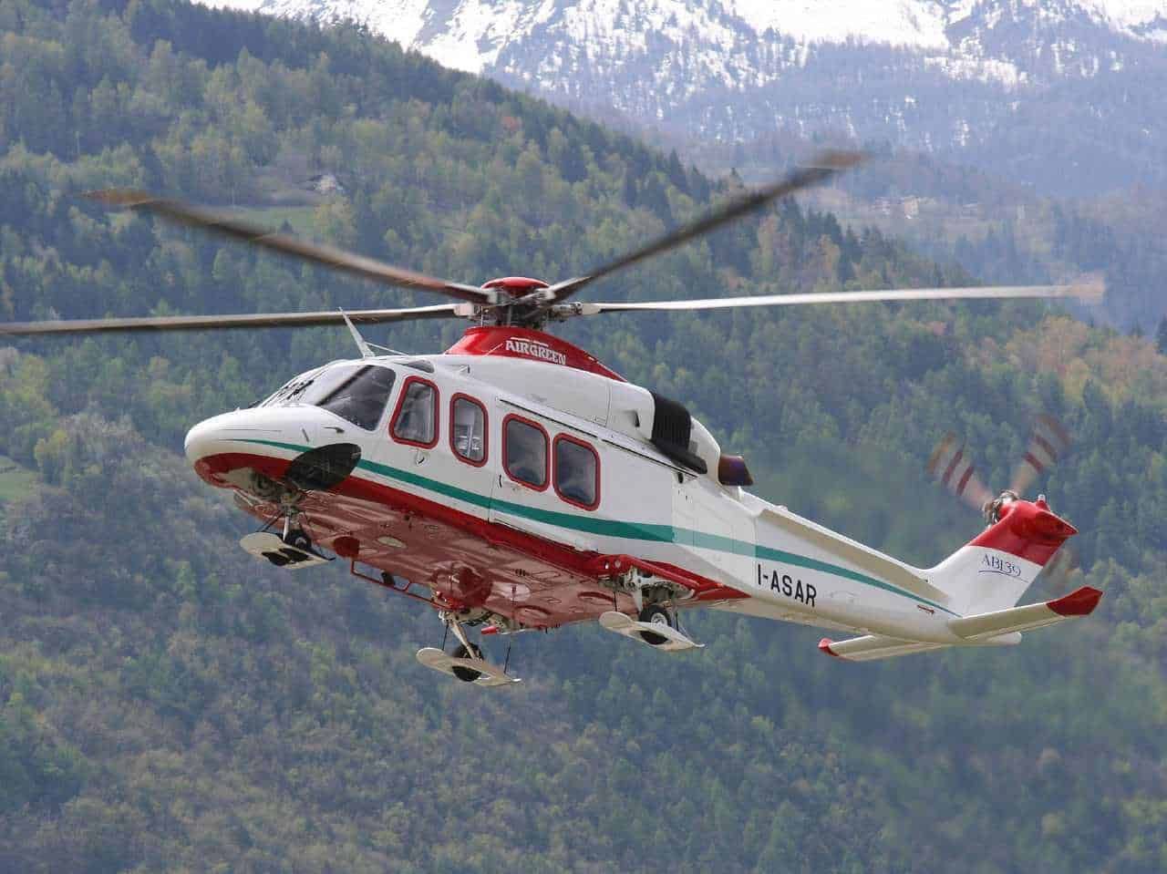 Aereo di emergenza in volo sopra montagne verdi, elicottero di soccorso per operazioni di pronto intervento, tecnologia aeronautica, elicottero di salvataggio in azione, foto di un'elicottero di emergenza.
