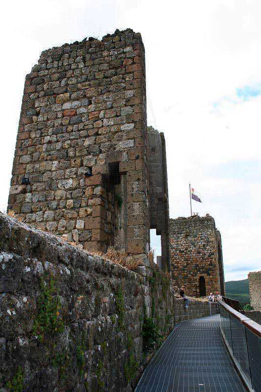 Antica torre in pietra con muratura medievale e percorso panoramico, simbolo di storia e cultura, visitabile come attrazione turistica nel castello.