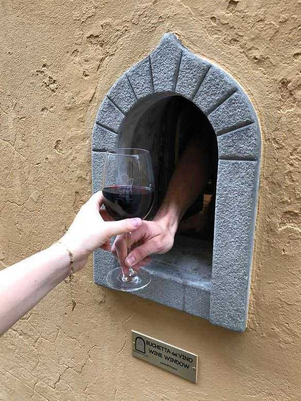 Buchette del vino a firenze: Vino rosso versato attraverso una finestra del vino in un muro in pietra, in una scena divertente di degustazione vino.