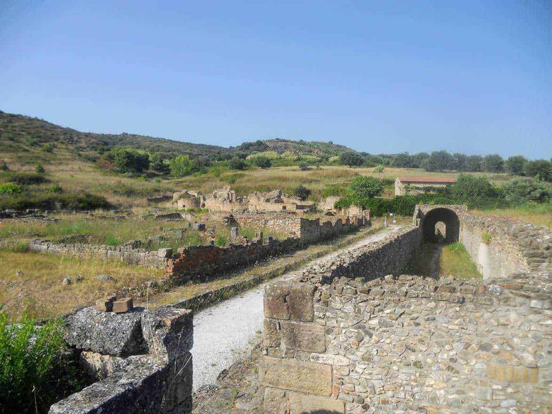 Costiera cilentana posti da visitare tra mare e terra 3 Antico sito archeologico di Roma antica con resti di mura e porte, immerso in un paesaggio collinare verde, ideale per appunti su storia e archeologia.