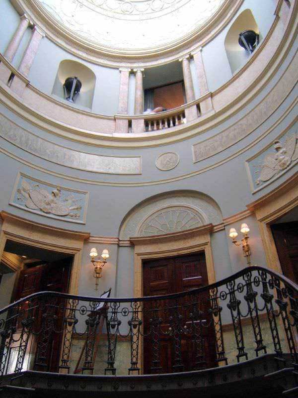 Elegante atrio interno con balconi in stile classico, decorazioni artistiche e illuminazione calda in un edificio storico di lusso.