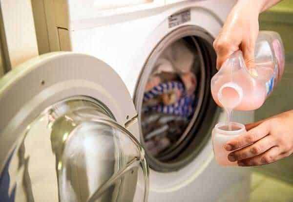 Lavatrice aperta con detersivo liquido che viene versato, cura dei capi di abbigliamento, lavaggio efficace, cura della lavanderia, immagine di pulizia domestica.