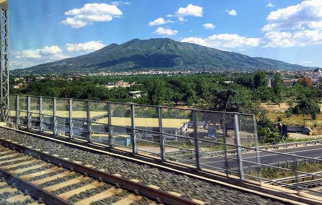 Muri romani antichi in pietra, resti di un sito archeologico storico in Italia, con un cielo blu e un'area verde circostante. Aperto al pubblico e ideale per appassionati di storia e archeologia.
