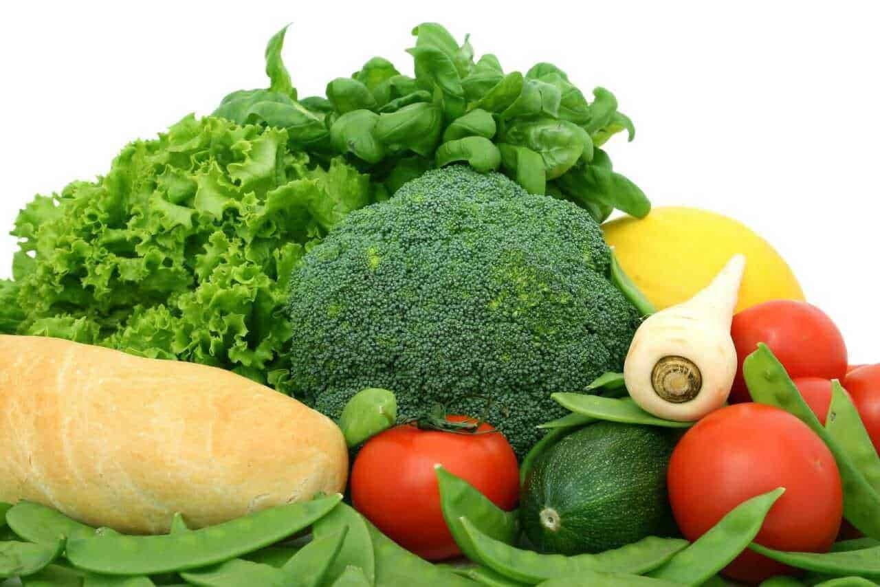 Verdure fresche e colorate in cesto di legno, tra cui lattuga, cavolo riccio, ravanelli e peperoni gialli, ideale per ricette salutari e piatti vegetariani di qualità.
