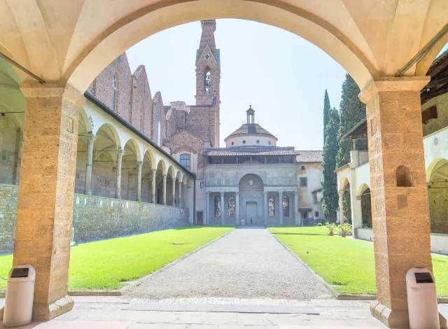 Affascinante vista di un antico monastero o convento storico con cortile interno, archi in pietra e chiesa con campanile in stile medievale, immerso in un ambiente tranquillo e spirituale.