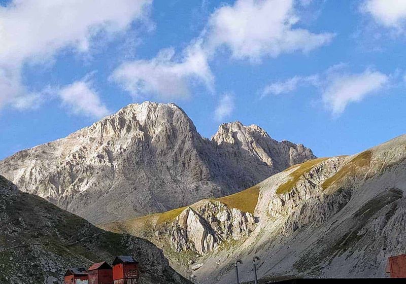 Dove andare in Abruzzo montagna estate 2 Abruzzo montagna d'estate: Montagne rocciose spettacolari nelle Alpi italiane con cielo azzurro e nuvole bianche, scenario naturale mozzafiato ideale per escursioni e turismo outdoor.