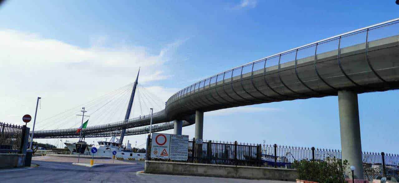 Innovativo ponte pedonale sospeso lungo il porto di La Spezia con vista mare e imbarcazioni. Architettura moderna e funzionale, perfetta per esplorare il centro storico e le attrazioni locali.