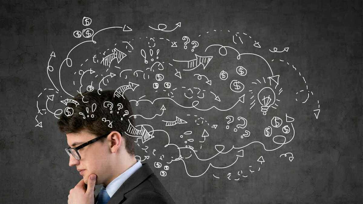 Pensatore con schizzi di idee, flowchart e simboli su lavagna nera, rappresenta creatività, brainstorming e processi di pensiero critico.