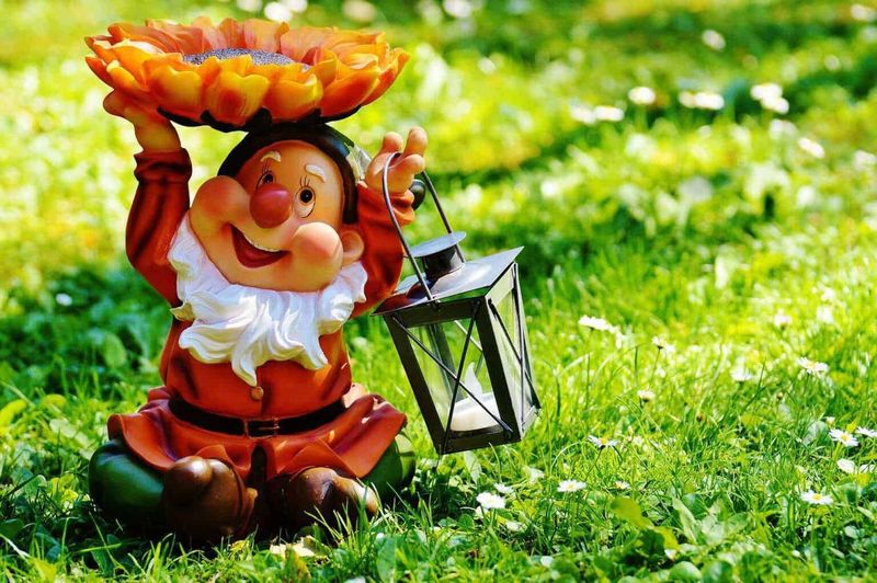 Gufo di terracotta con lanterna e fiori in giardino, decorazione natalizia, decorazioni festive estive, ambientazione outdoor, oggetto di decorazione per esterni.