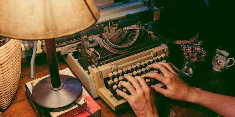 Macchina da scrivere d'epoca su scrivania in legno con lampada, ambientazione vintage e creativa