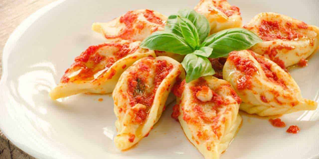 Pomodori ripieni di formaggio e basilico su piatto bianco, deliziosi antipasti italiani con salsa di pomodoro e mozzarella. Ricetta semplice e gustosa, perfetta per ogni occasione.