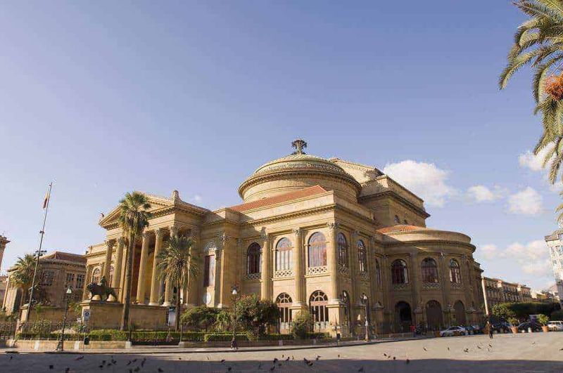 25 luoghi da visitare a Palermo e dintorni in stile arabo normanno 2 Palermo arabo-normanna: Elegante edificio storico in stile classico con colonne e cupola, situato in una tranquilla zona urbana decorata con palme, perfetto esempio di architettura monumentale italiana.