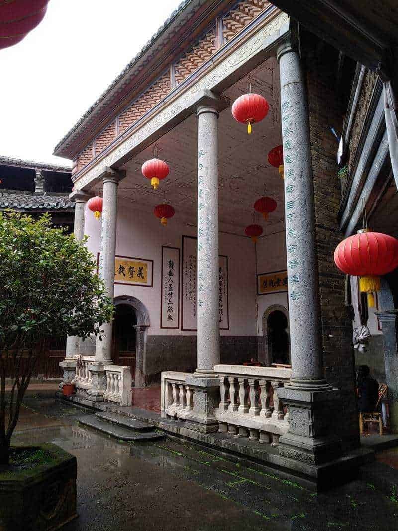 Elegante portico con colonne in pietra, decorato con lanterne rosse cinesi e pannelli artistici, in un tradizionale ambiente giapponese o cinese, ideale per foto di architettura asiatica e cultura orientale.
