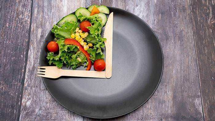 Perdere peso velocemente in modo sano 3 Verdura fresca e colorata in una ciotola di legno su un piatto nero, simbolo di alimentazione sana e dieta mediterranea.