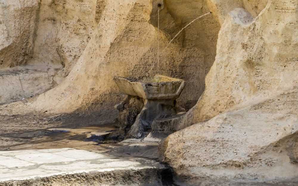 Antico abbeveratoio in pietra naturale, fonte d'acqua rustica e tradizionale, immersa in un ambiente in pietra, perfetta per articoli sul recupero storico e cultura tradizionale.