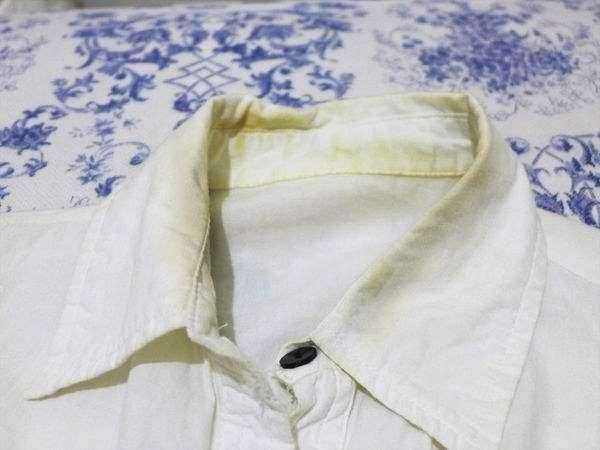 Candeggina dove non usarla, 12 errori 2 Camicia bianca classica in lino su sfondo di tovaglia blu e bianca con motivi floreali, perfetta per look eleganti e casual, ideale per l'estate e le occasioni formali.