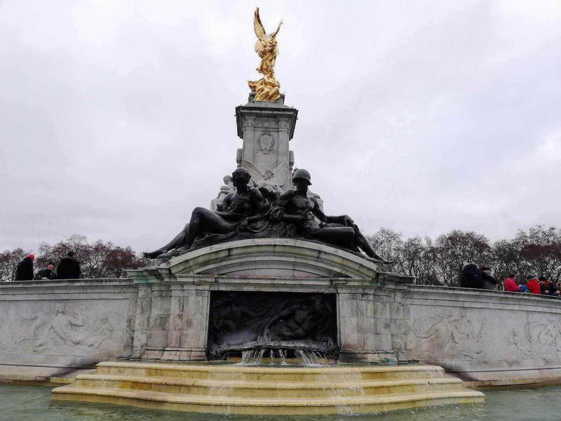 Fontane e acqua potabile: origini dall'antichità ai tempi moderni 6 Statua monumentale con figure in bronzo e dettagli dorati, scenario di piazza pubblica con persone che visitano il monumento, ambientazione storica e culturale a Londra.