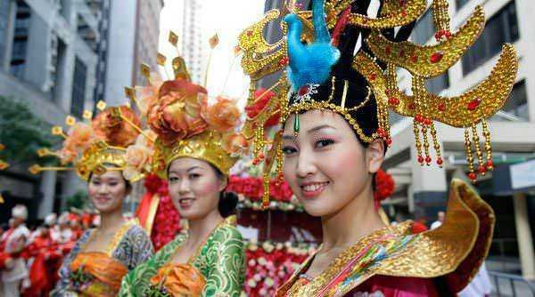 Vedi immagini di donne in costumi tradizionali asiatici durante un festival culturale all'aperto.