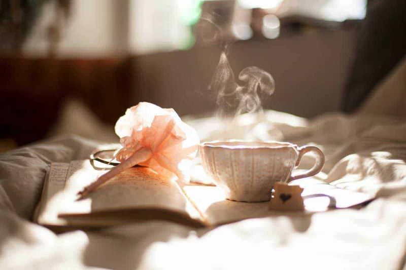 Cultura e tradizioni della Cina, 12 usanze interessanti 6 Profumo di tè caldo, fiamma che sprigiona vapore su una tazza da tè e libro aperto, atmosfera tranquilla e rilassante, ideale per la lettura e il relax.