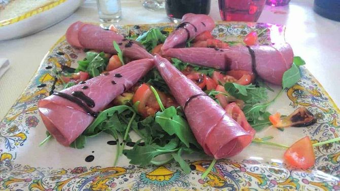 Finger foods: come preparare un aperitivo semplice e veloce 2 Salumi di prosciutto crudo avvolti intorno a insalata mista con pomodori e salsa balsamica in un piatto decorato tradizionale italiano Altezza, salumi prosciutto crudo, insalata mista, pomodori, salsa balsamica, piatto decorato italiano.