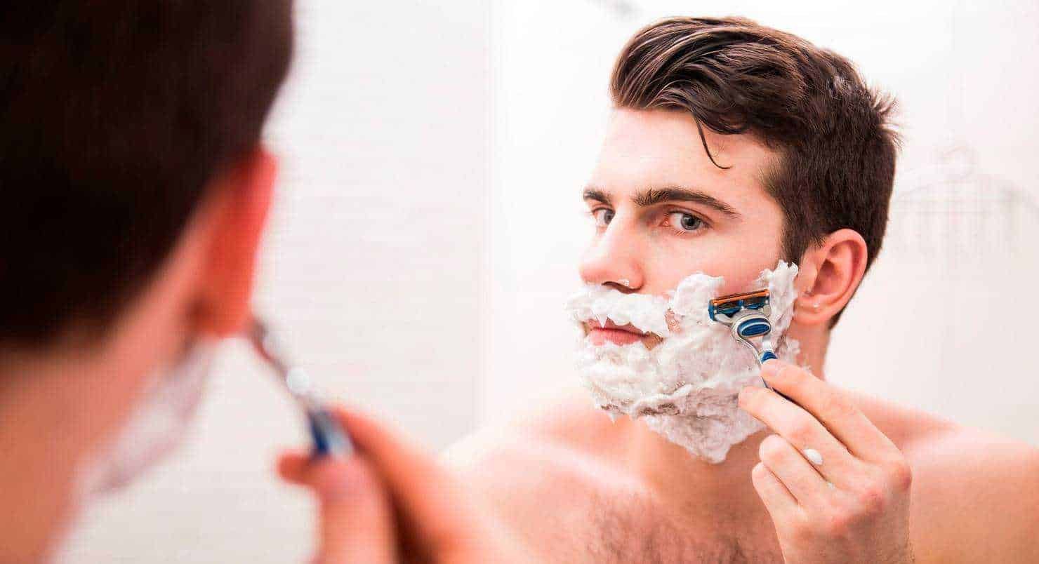 L'uomo si sta radendo, applicando schiuma da barba, in bagno, cura della pelle maschile, routine di grooming, immagine di cura personale, sensibilità verso l'igiene e l'aspetto esteriore, stile di vita quotidiano.