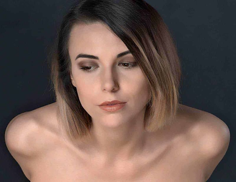 8 Tagli di capelli donna che ringiovaniscono per donne over 60 4 Bellissima donna giovane con trucco naturale, capelli castani corti, sguardo sereno e pelle luminosa, primo piano di bellezza femminile, modella con espressione irresistibile, ritratto di stile e eleganza femminile.