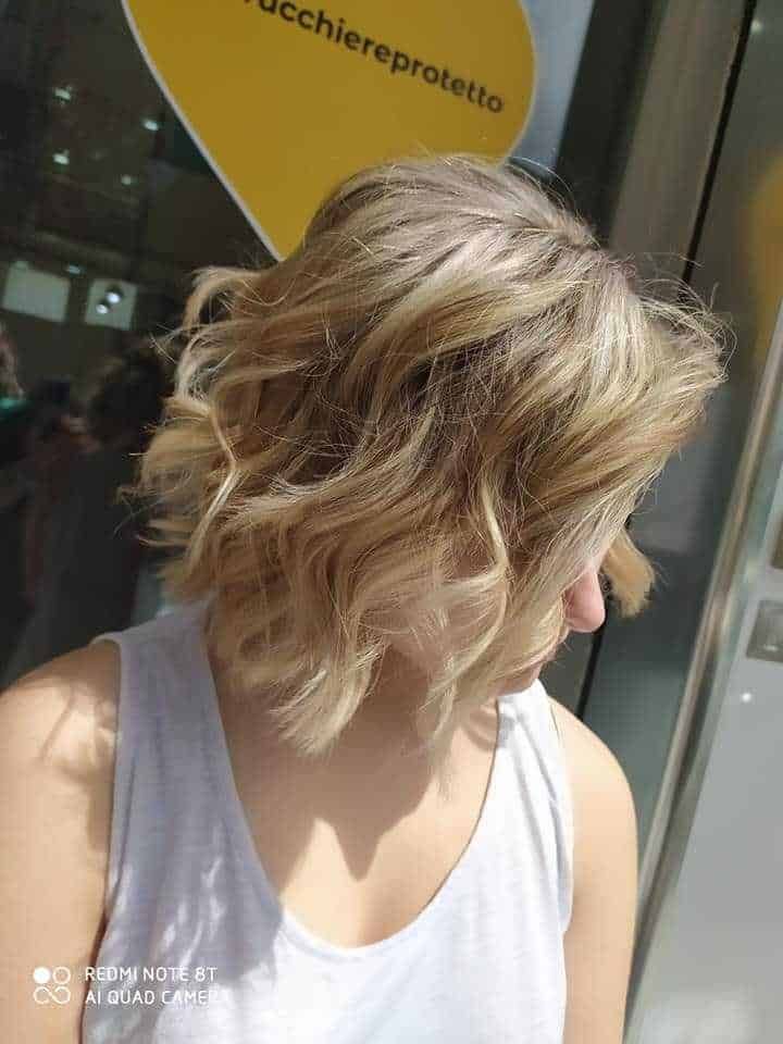 Donna con capelli corti ondulati biondi apllicazione di taglio di capelli moderni e stile capelli eleganti e alla moda.