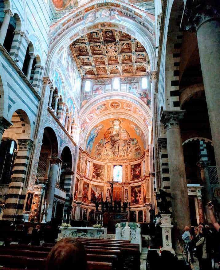 Alt text: Interno della Basilica di San Francesco d'Assisi, con affreschi e architettura barocca, particolare delle decorazioni celestiali e dell'altare maggiore.