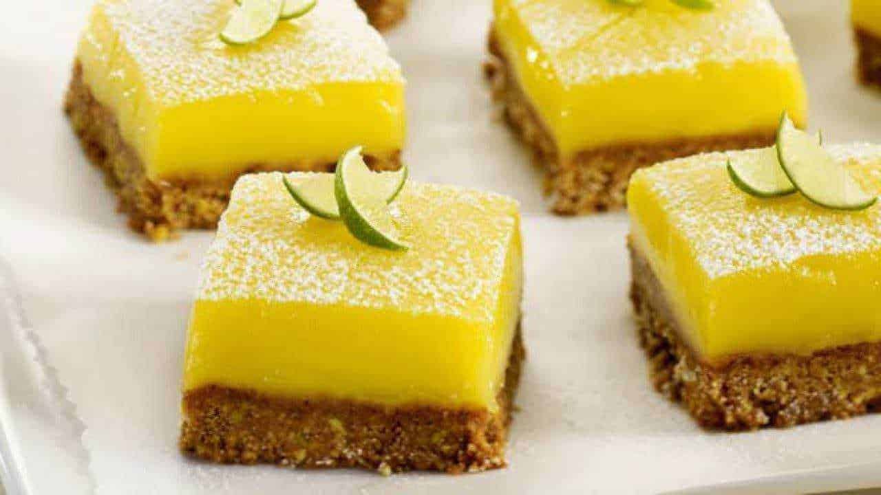 Torta al limone con base di biscotti, decorata con lime e zucchero a velo, perfetta come dessert fresco e sfizioso.