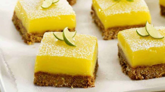 Dolci freddi veloci e leggeri da fare in casa 5 Torta al limone con base di biscotti, decorata con lime e zucchero a velo, perfetta come dessert fresco e sfizioso.