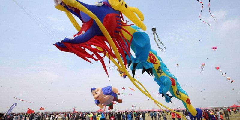 Le cose più curiose sulla Cina e sui cinesi, dalla matematica cinese: 60 stranezze 4 Colorati aquiloni a forma di dragone in cielo durante un festival, con una folla di persone che ammira lo spettacolo all'aperto. Atmosfera vivace e colorata, ideale per appassionati di eventi e cultura popolare.