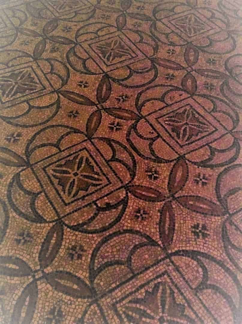 Motivo geometrico in mosaico di pietra e ceramica, decorazioni artigianali di stile tradizionale, pavimento in edifici storici italiani, dettagli decorativi antichi per interni raffinati.