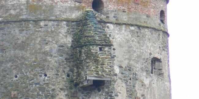 Vecchia torre di castello in pietra con merlature e feritoie, rappresentazione di un patrimonio storico e architettonico italiano.