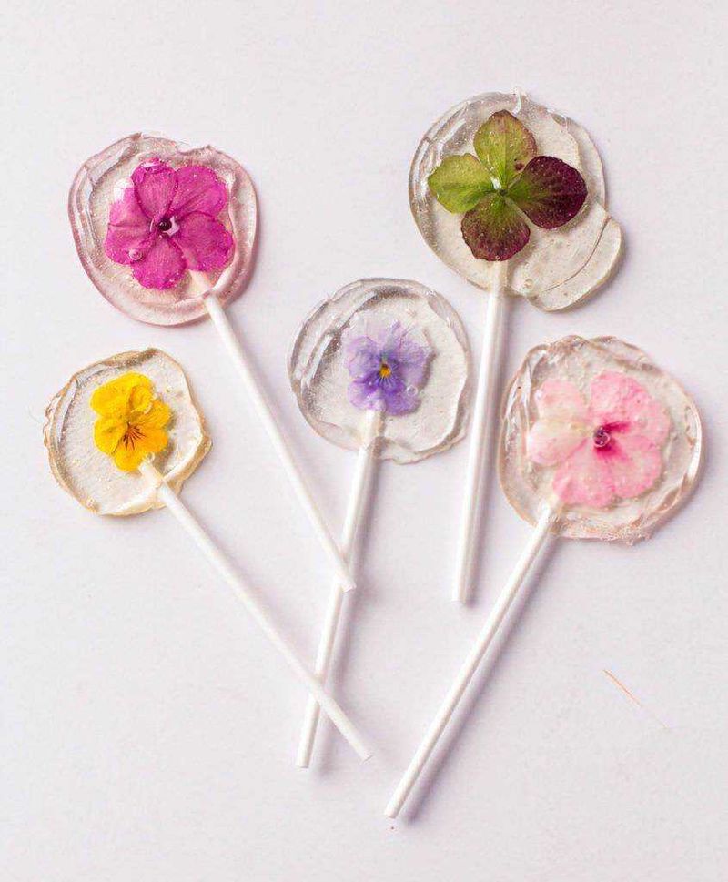 Lecca lecca artigianali con marmellata di albicocche 4 Lollipop a forma di fiore multicolore su sfondo giallo brillante.
