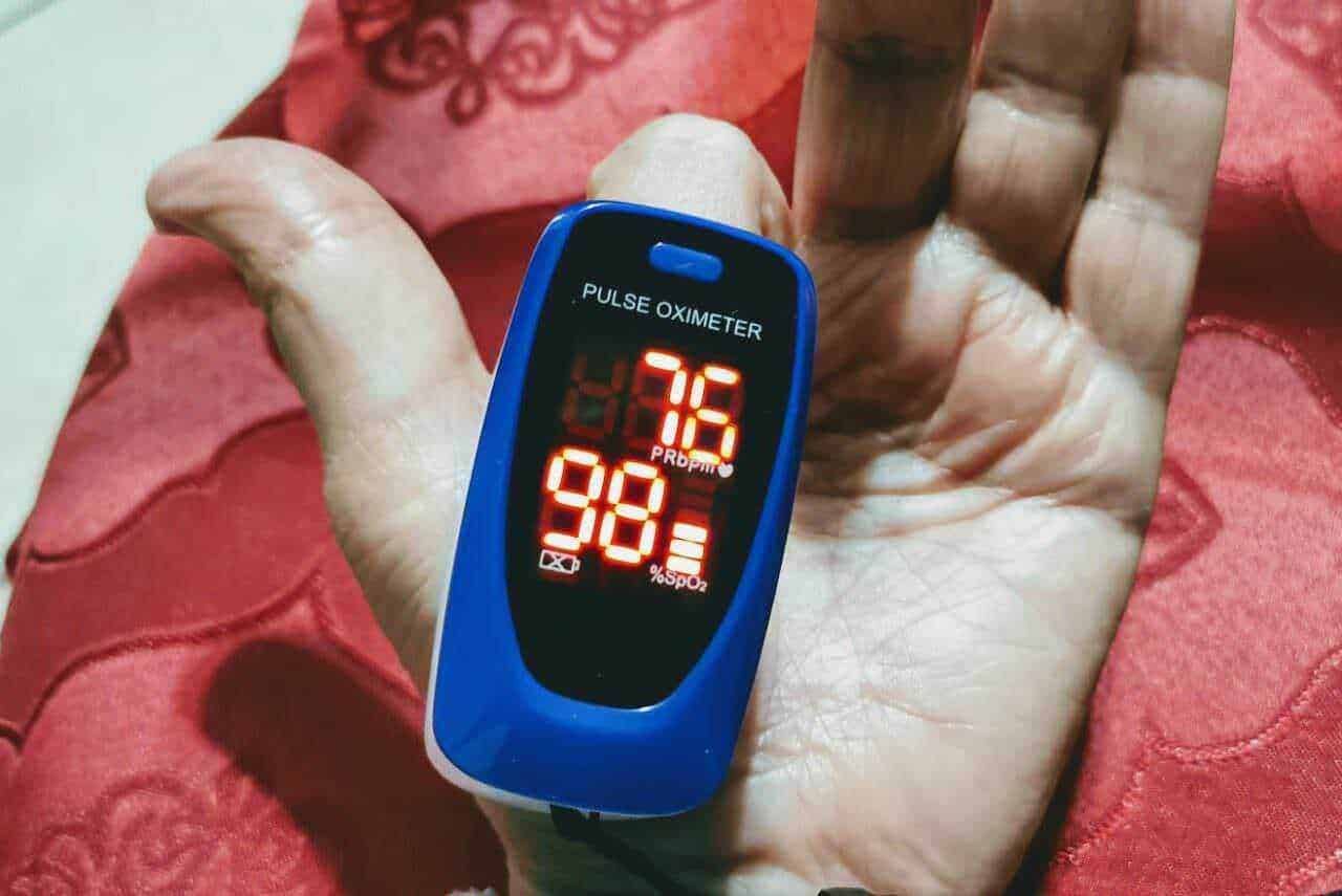 Pulsossimetro digitale mostrando saturazione di ossigeno e frequenza cardiaca su una mano. Strumento medico essenziale per monitorare i livelli di ossigeno nel sangue, particolarmente utile per pazienti con problemi respiratori.