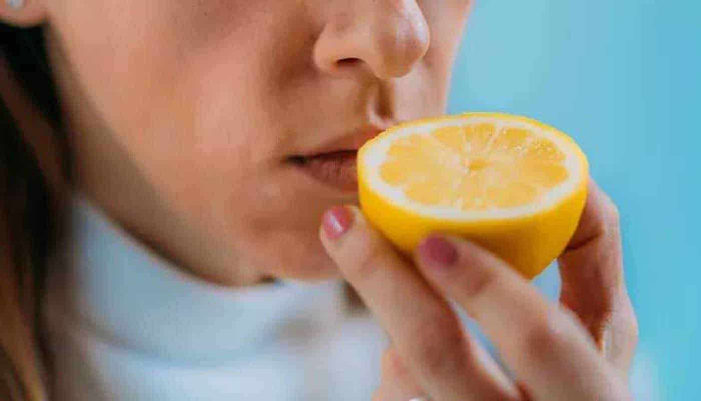 Limone fresco e succoso mentre si avvicina alle labbra per un assaggio, evidenziando benefici nutrizionali e gustativi, perfetto per contenuti su alimentazione sana e benessere naturale.