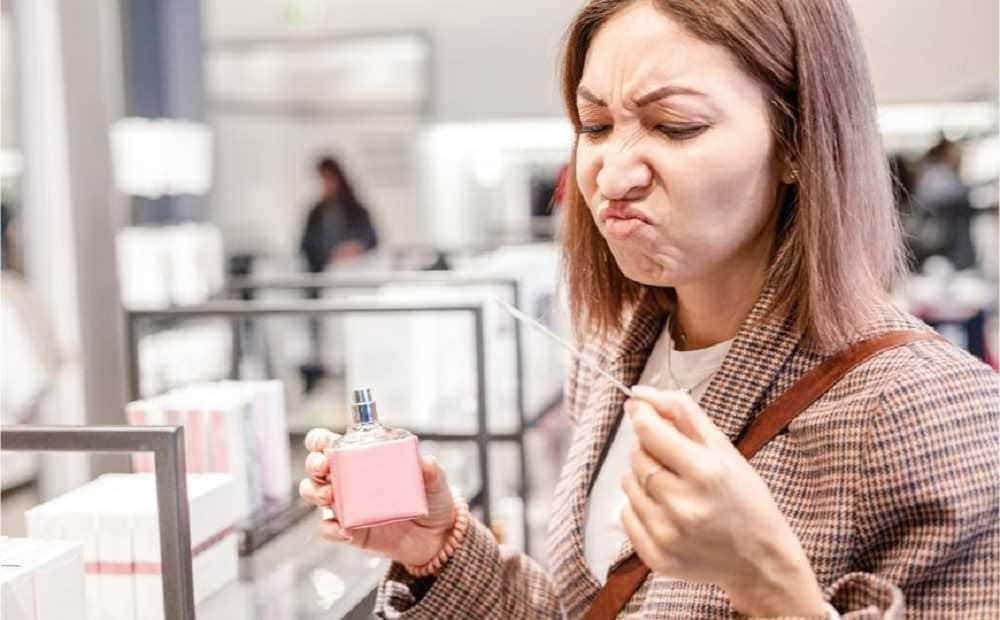 Fragile donna che annusa un flacone di profumo in negozio, moda e shopping.