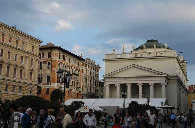 Vicolo con vista sul Canale di Genova, con edifici storici e barche attraccate, sotto un cielo nuvoloso.