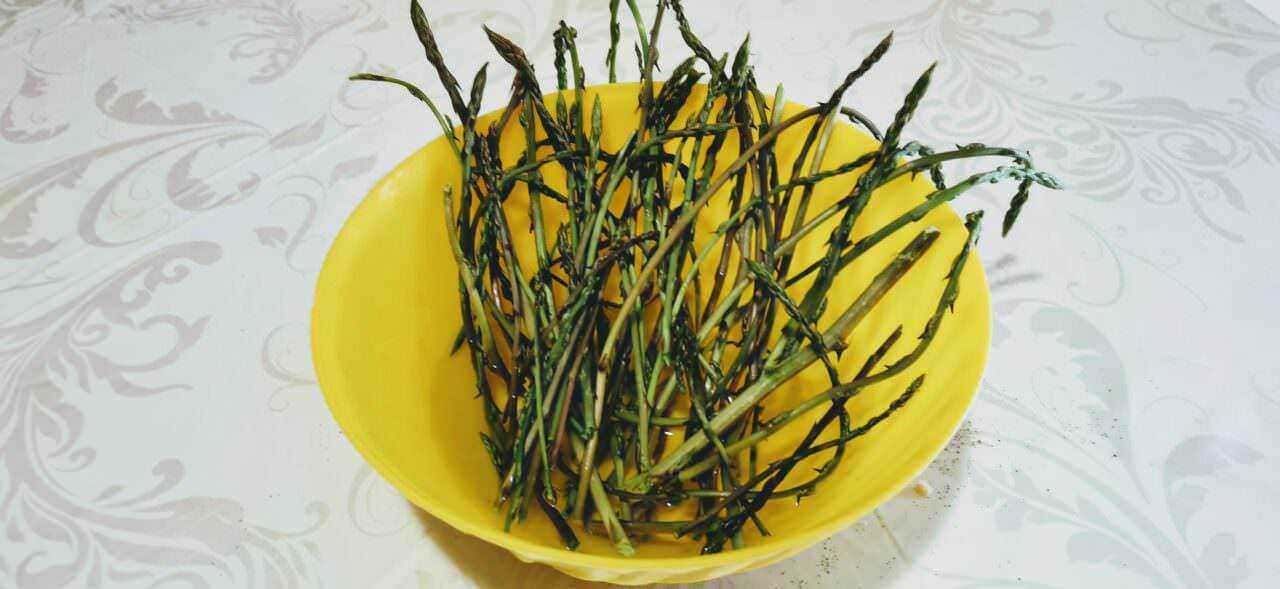 Asparagi freschi su piatto decorato con motivi floreali, simbolo di cucina sana e alimentazione naturale.