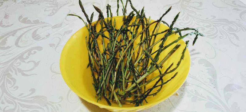 Asparagi proprietà, composizione e utilizzo. 3 Asparagi freschi su piatto decorato con motivi floreali, simbolo di cucina sana e alimentazione naturale.