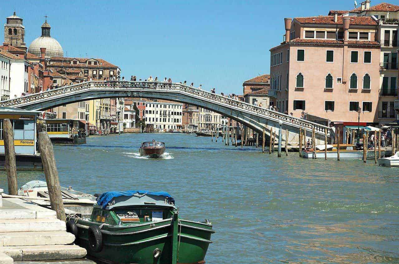 Venedig Ponte di Rialto con gondole e palazzi storici sotto cielo blu soleggiato, atmosfera romantica e turistica, immagini di viaggio e cultura veneziana, destinazione turistica ideale.